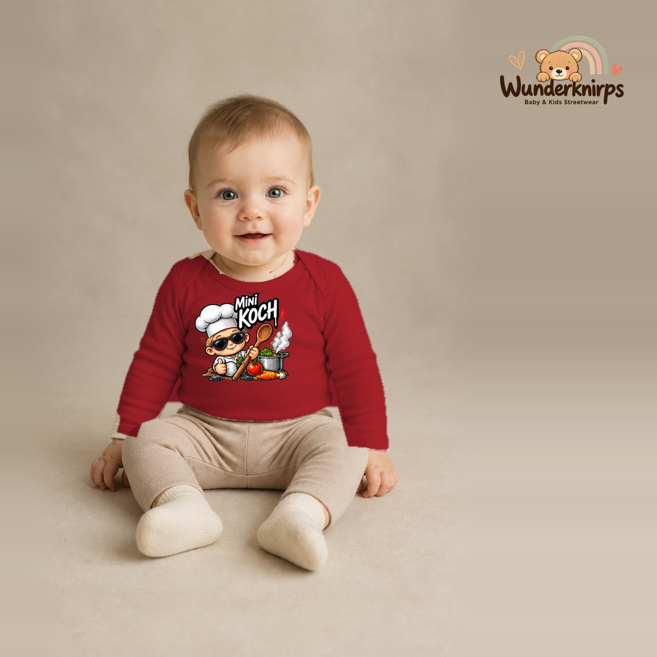 Babybody für Jungen in Rot mit Motiv „Mini Koch“, getragen von einem Kind – Wunderknirps.