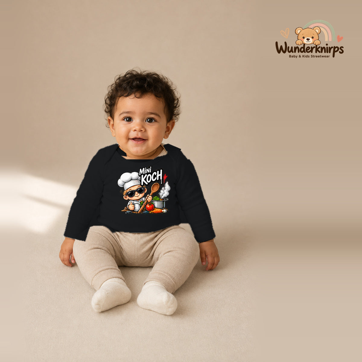 Babybody für Jungen in Schwarz mit Motiv „Mini Koch“, getragen von einem Kind – Wunderknirps.