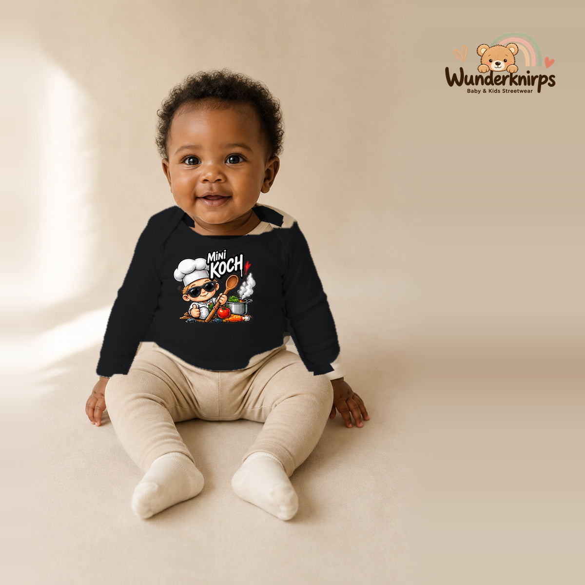 Babybody für Mädchen in Schwarz mit Motiv „Mini Koch“, getragen von einem Kind – Wunderknirps.