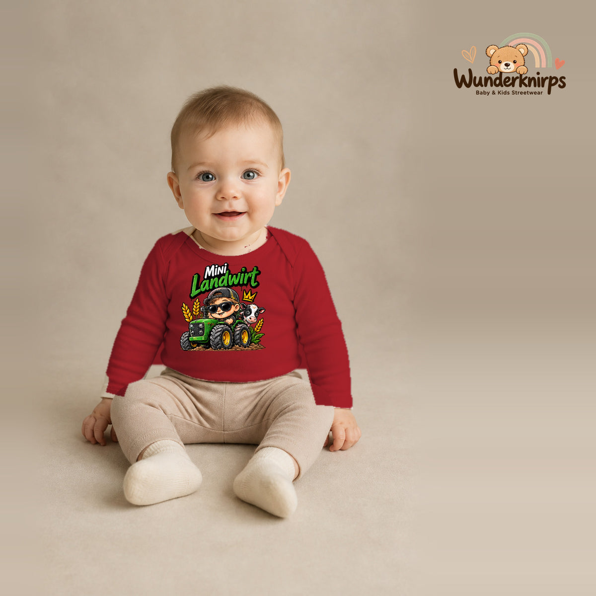 Babybody für Jungen in Rot mit Motiv „Mini Landwirt“, getragen von einem Kind – Wunderknirps.