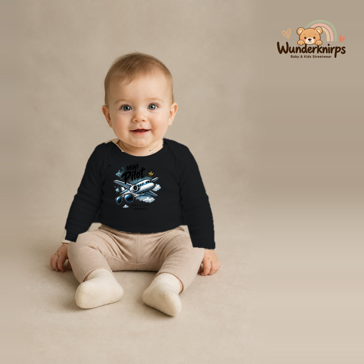 Babybody für Jungen in Schwarz mit Motiv „Mini Pilot“, getragen von einem Kind – Wunderknirps.
