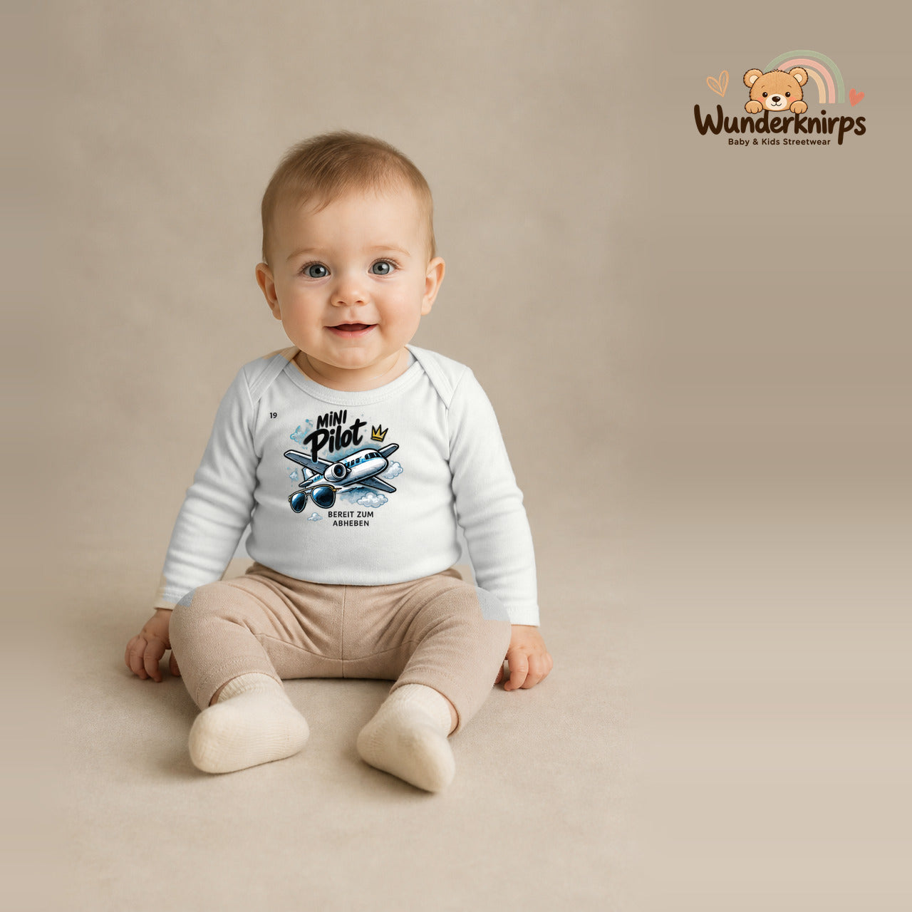 Babybody für Jungen in Weiß mit Motiv „Mini Pilot“, getragen von einem Kind – Wunderknirps.