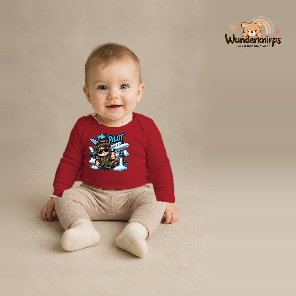 Babybody für Jungen in Rot mit Motiv „Mini Pilot“, getragen von einem Kind – Wunderknirps.