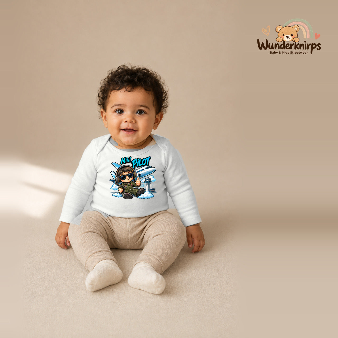 Babybody für Jungen in Weiß mit Motiv „Mini Pilot“, getragen von einem Kind – Wunderknirps.