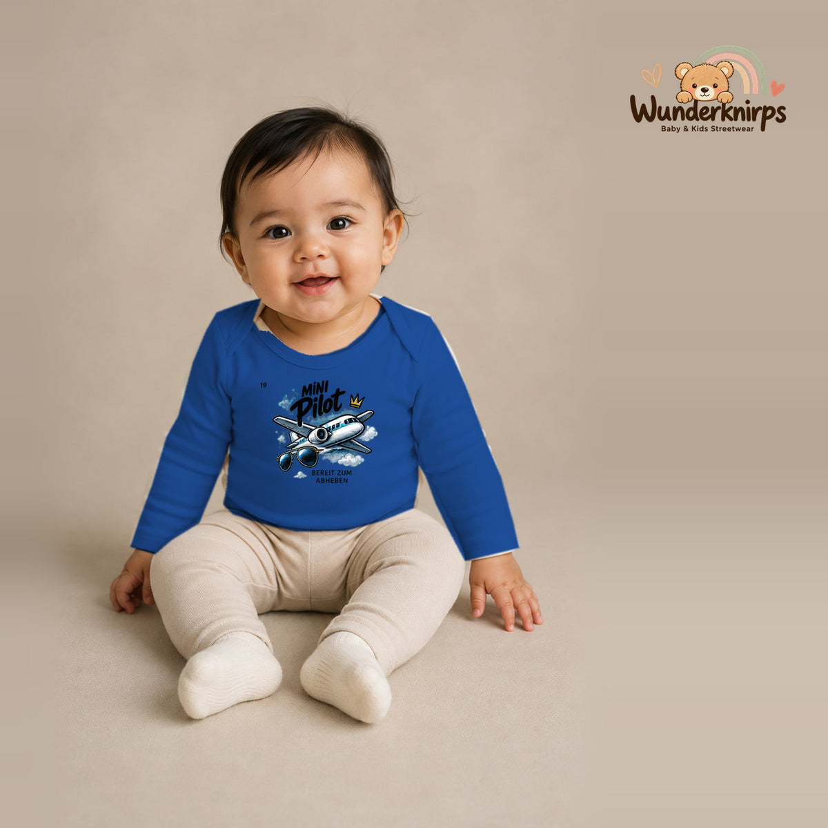 Babybody für Mädchen in Blau mit Motiv „Mini Pilot“, getragen von einem Kind – Wunderknirps.