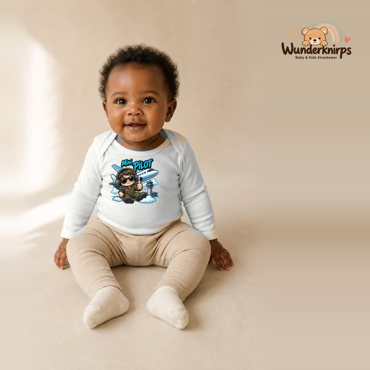 Babybody für Mädchen in Weiß mit Motiv „Mini Pilot“, getragen von einem Kind – Wunderknirps.