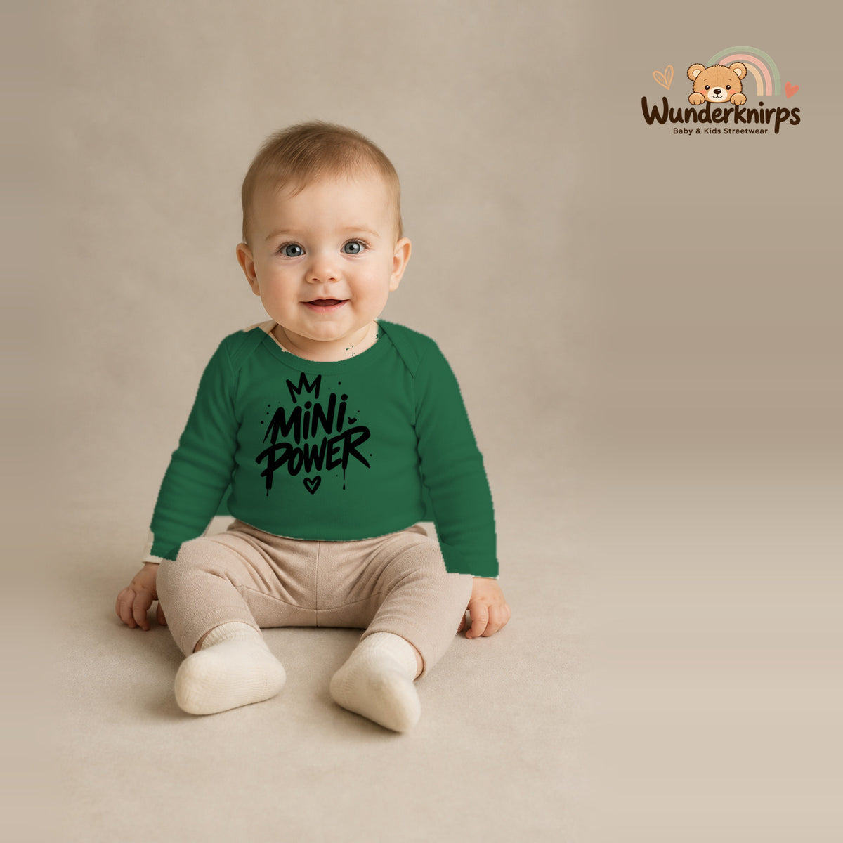 Babybody für Jungen in Grün mit Motiv „Mini Power“, getragen von einem Kind – Wunderknirps.