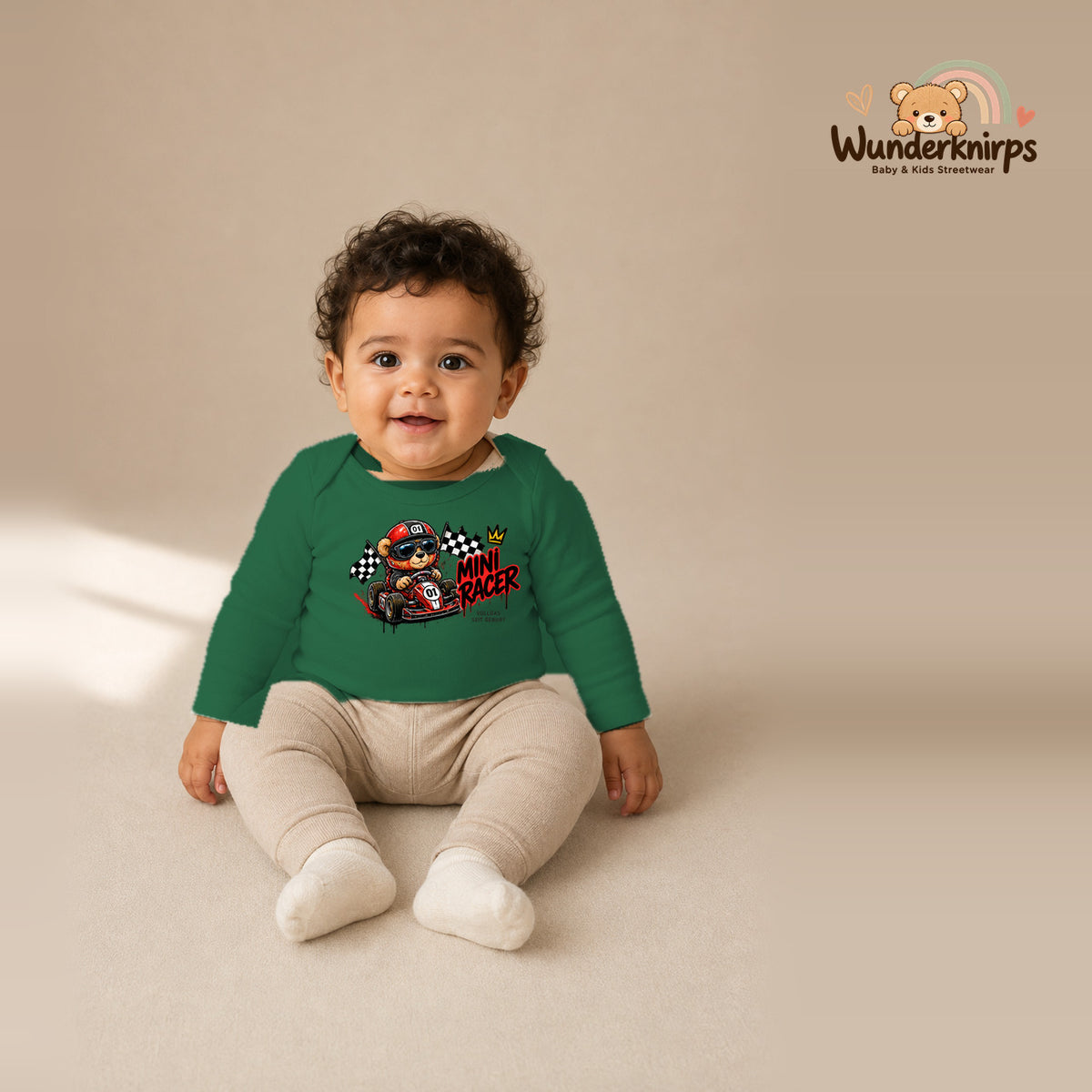 Babybody für Jungen in Grün mit Motiv „Mini Racer“, getragen von einem Kind – Wunderknirps.