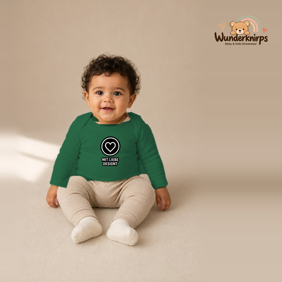 Babybody für Jungen in Grün mit Motiv „Mit Liebe designt“, getragen von einem Kind – Wunderknirps.