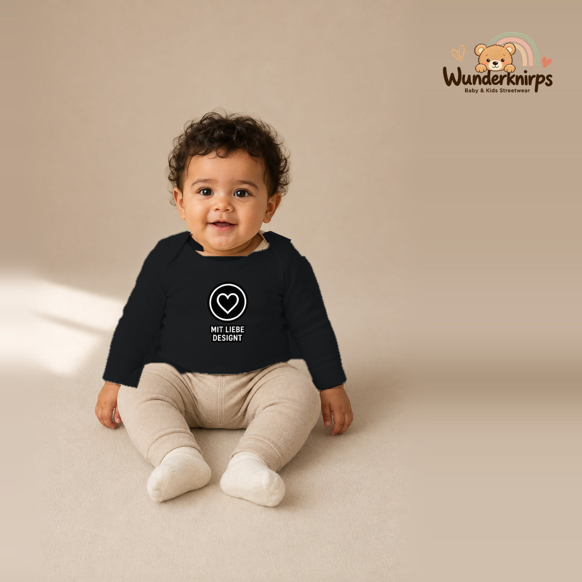 Babybody für Jungen in Schwarz mit Motiv „Mit Liebe designt“, getragen von einem Kind – Wunderknirps.