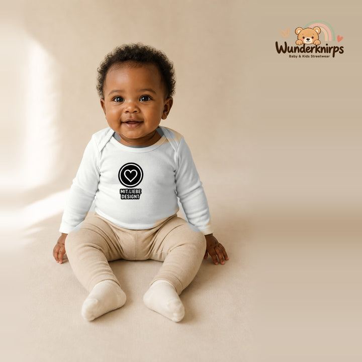 Babybody für Mädchen in Weiß mit Motiv „Mit Liebe designt“, getragen von einem Kind – Wunderknirps.