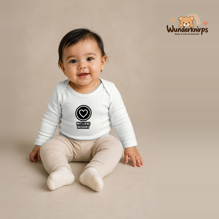 Babybody für Mädchen in Weiß mit Motiv „Mit Liebe designt“, getragen von einem Kind – Wunderknirps.