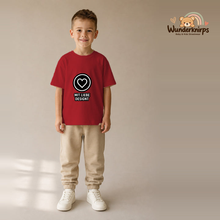 T-Shirt für Jungen in Rot mit Motiv „Mit Liebe designt“, getragen von einem Kind – Wunderknirps.