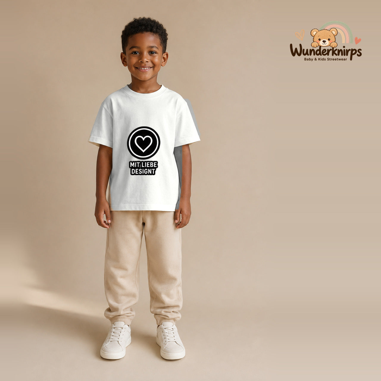 T-Shirt für Jungen in Weiß mit Motiv „Mit Liebe designt“, getragen von einem Kind – Wunderknirps.