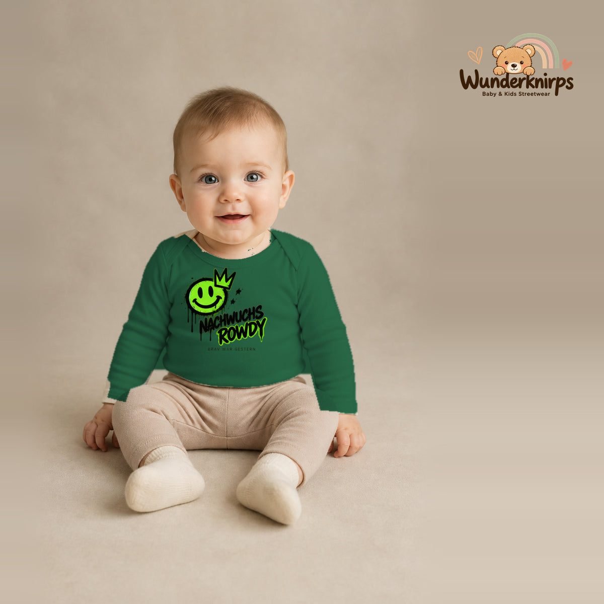 Babybody für Jungen in Grün mit Motiv „Nachwuchs Rowdy“, getragen von einem Kind – Wunderknirps.