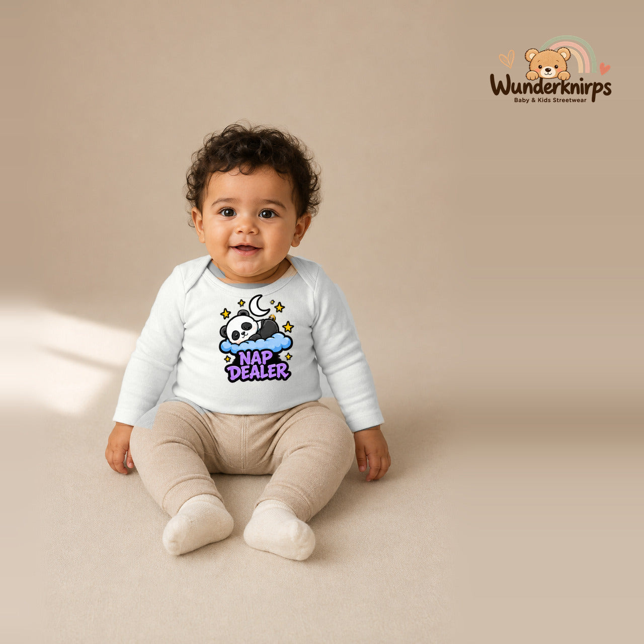 Babybody für Jungen in Weiß mit Motiv „Nap Dealer“, getragen von einem Kind – Wunderknirps.