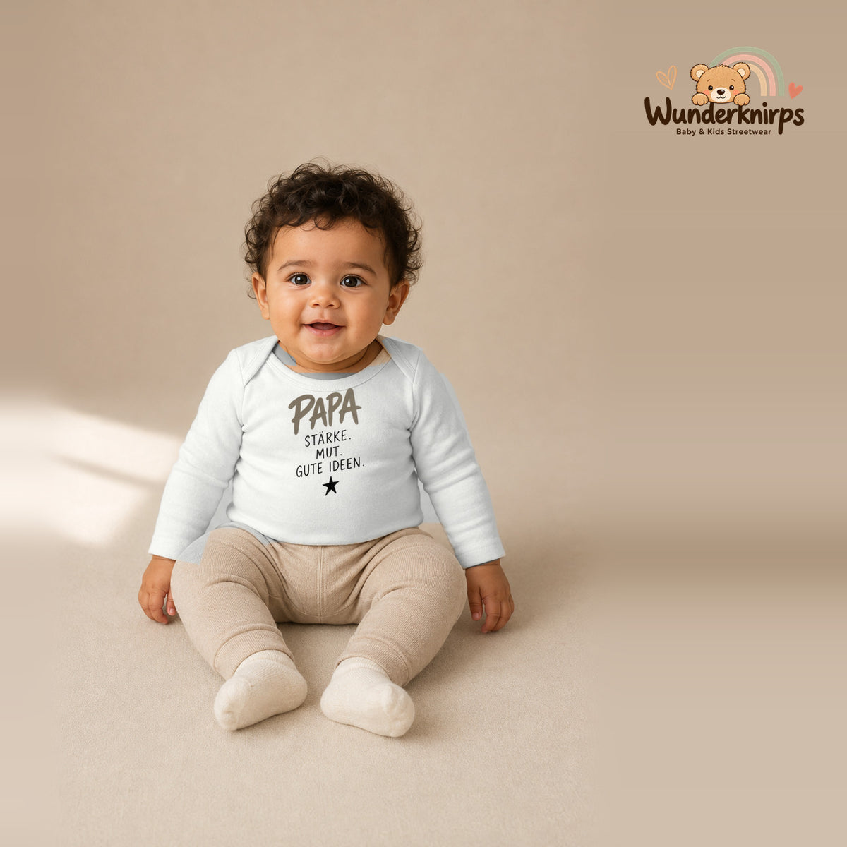 Babybody für Jungen in Weiß mit Motiv „Papa Stärke“, getragen von einem Kind – Wunderknirps.