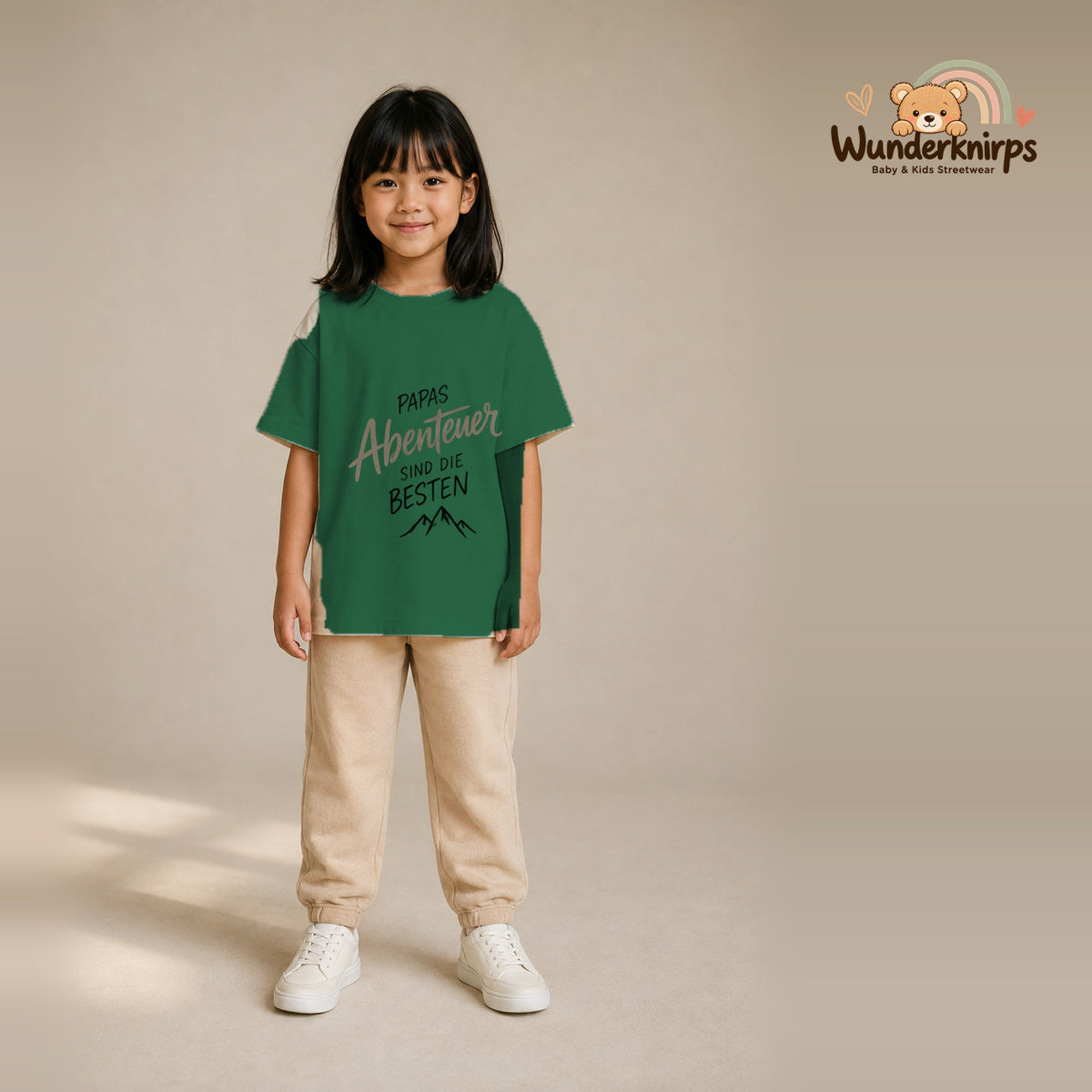 T-Shirt für Mädchen in Grün mit Motiv „Papas Abenteuer“, getragen von einem Kind – Wunderknirps.