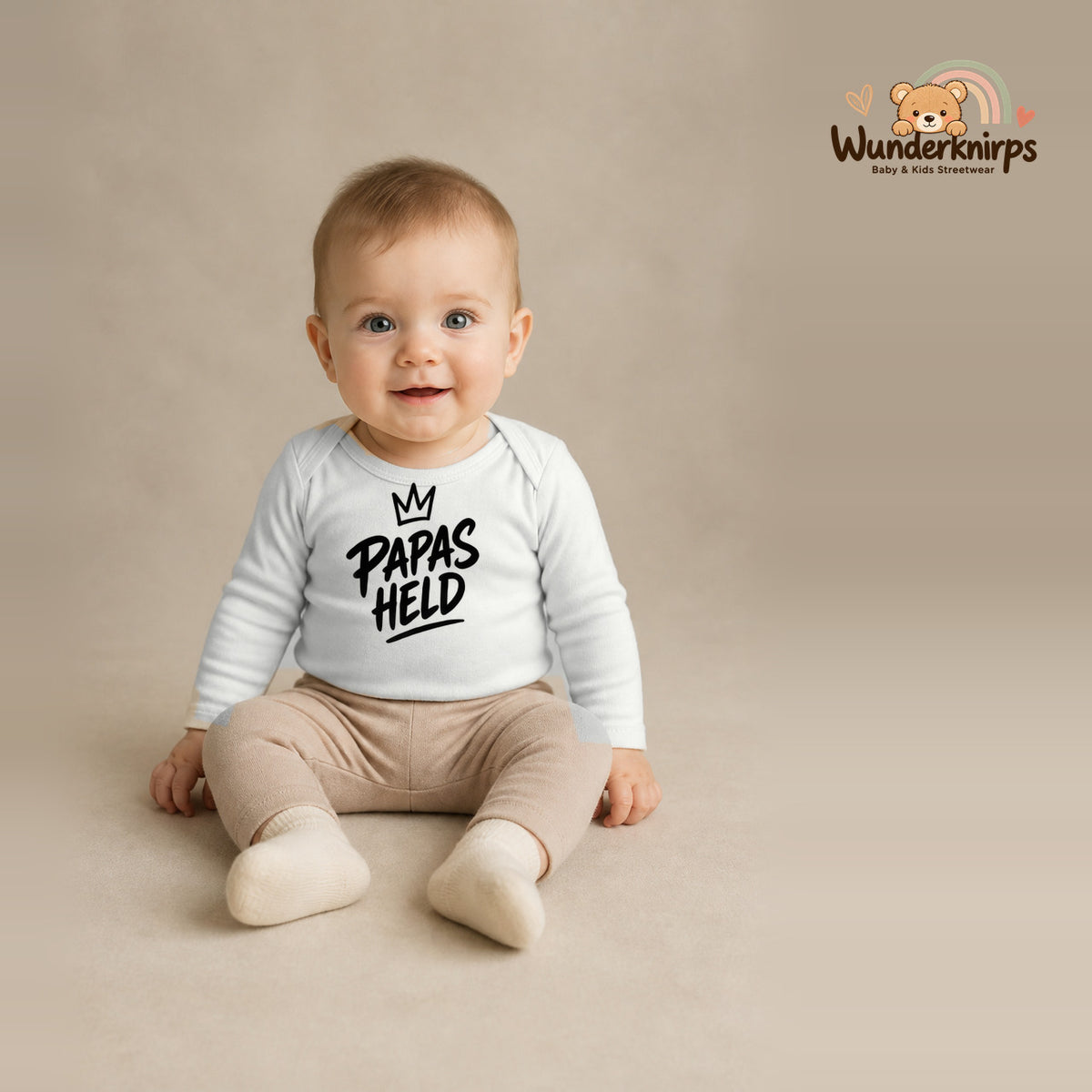 Babybody für Jungen in Weiß mit Motiv „Papas Held“, getragen von einem Kind – Wunderknirps.
