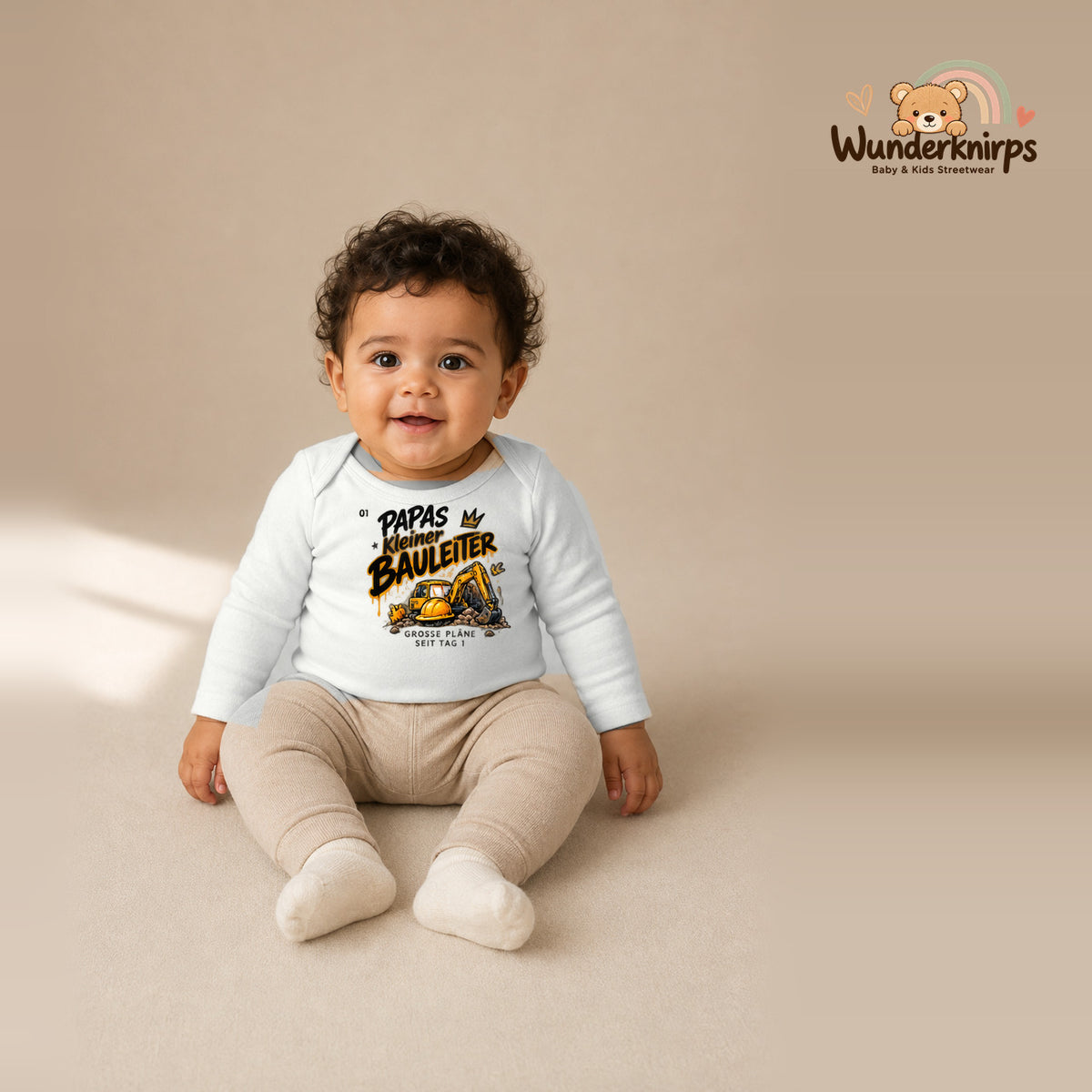 Babybody für Jungen in Weiß mit Motiv „Papas kleiner Bauleiter“, getragen von einem Kind – Wunderknirps.