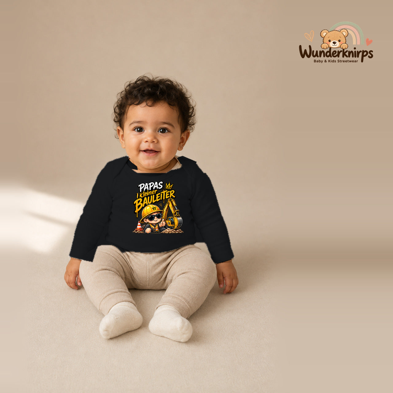 Babybody für Jungen in Schwarz mit Motiv „Papas kleiner Bauleiter“, getragen von einem Kind – Wunderknirps.