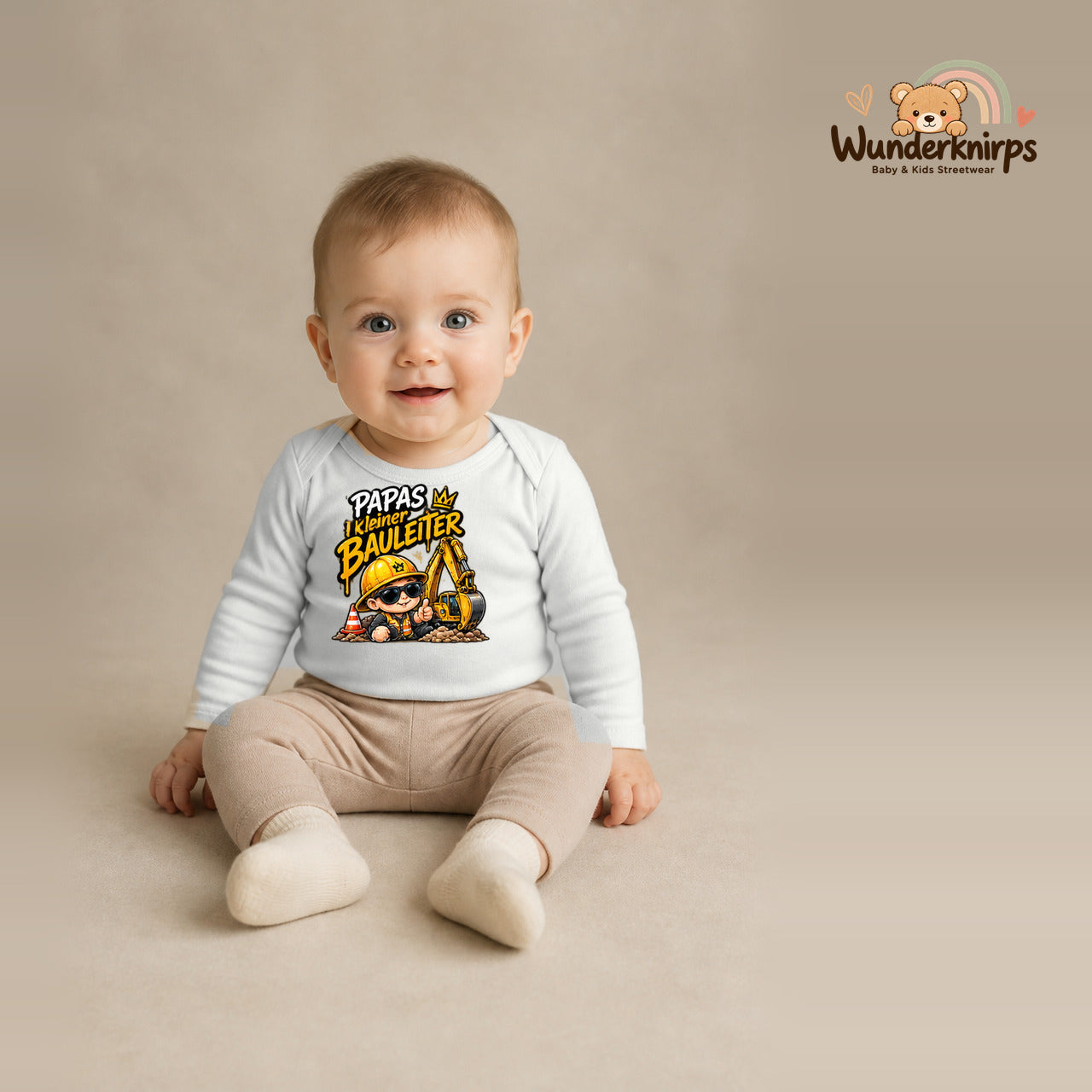 Babybody für Jungen in Weiß mit Motiv „Papas kleiner Bauleiter“, getragen von einem Kind – Wunderknirps.