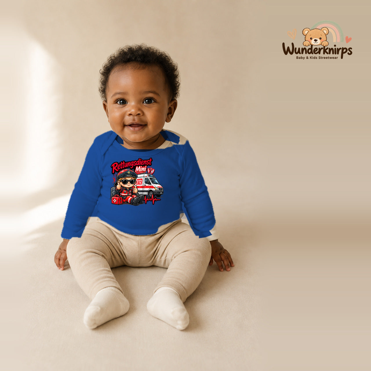 Babybody für Mädchen in Blau mit Motiv „Rettungsdienst Mini“, getragen von einem Kind – Wunderknirps.