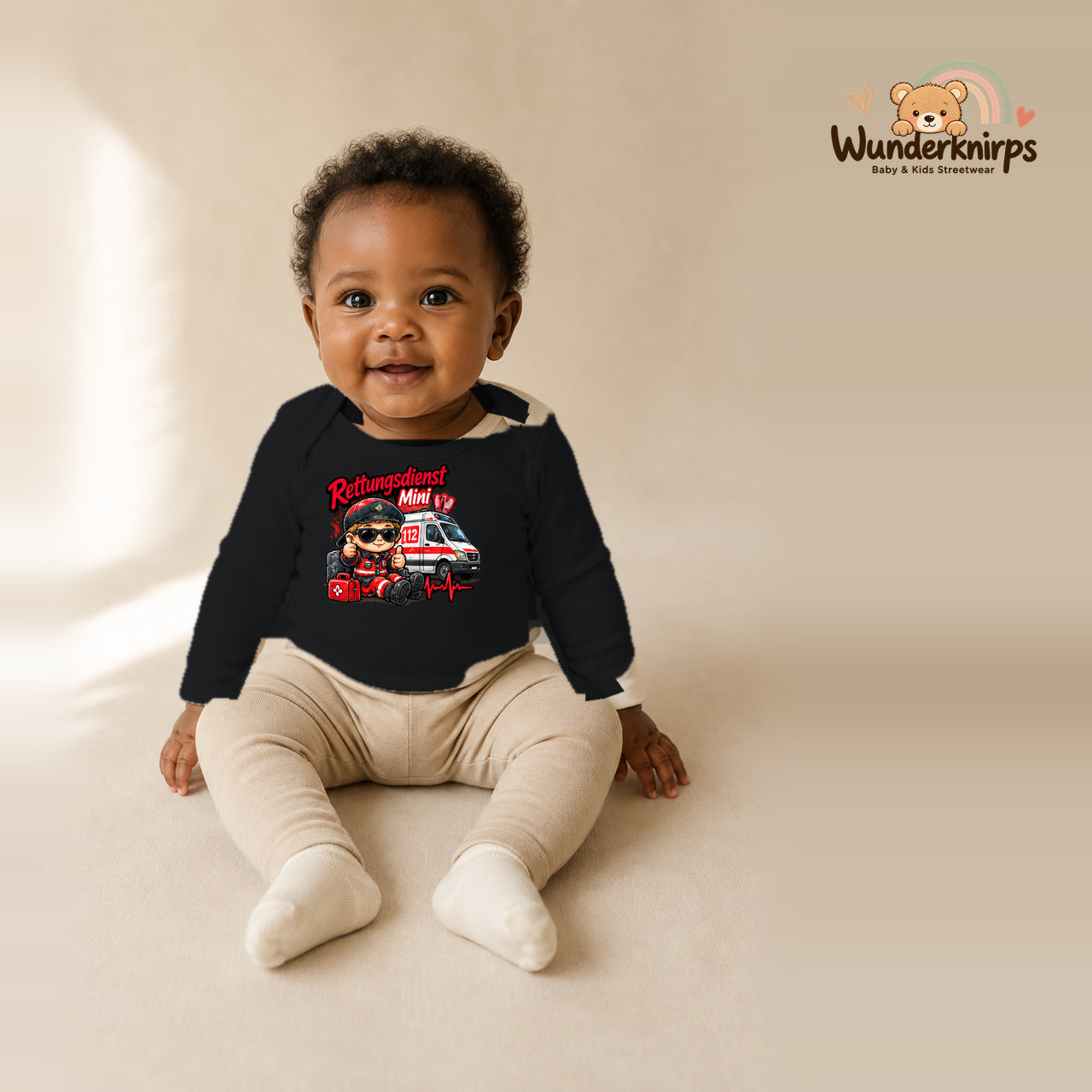 Babybody für Mädchen in Schwarz mit Motiv „Rettungsdienst Mini“, getragen von einem Kind – Wunderknirps.