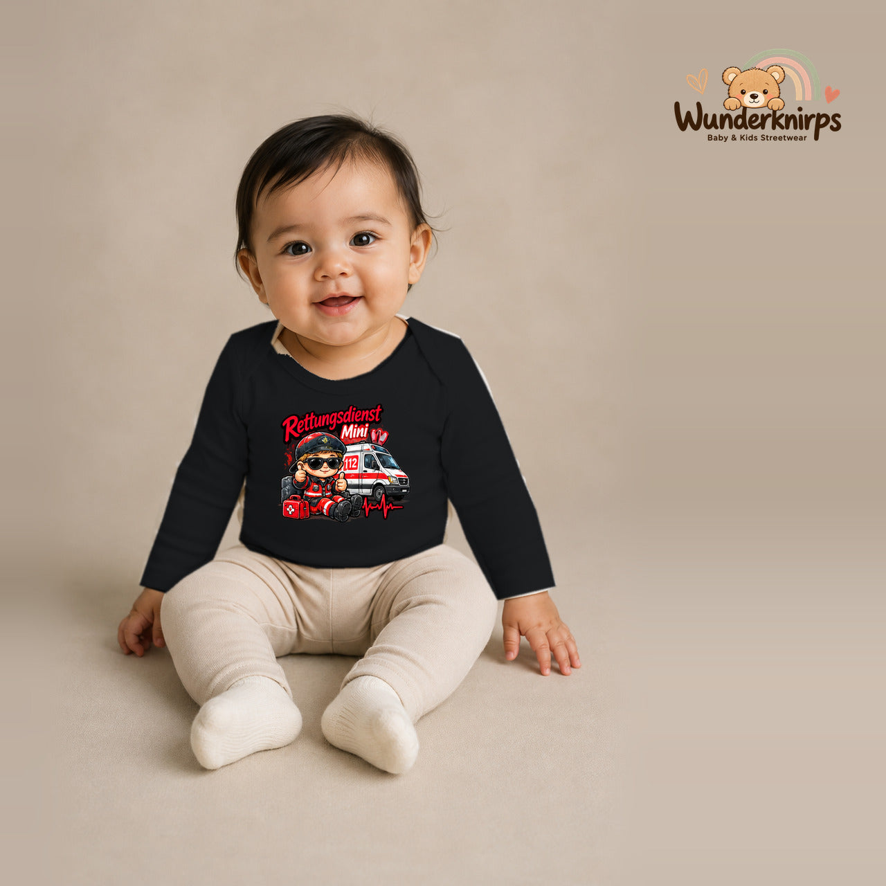 Babybody für Mädchen in Schwarz mit Motiv „Rettungsdienst Mini“, getragen von einem Kind – Wunderknirps.