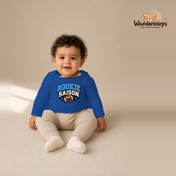 Babybody für Jungen in Blau mit Motiv „Rookie Saison“, getragen von einem Kind – Wunderknirps.