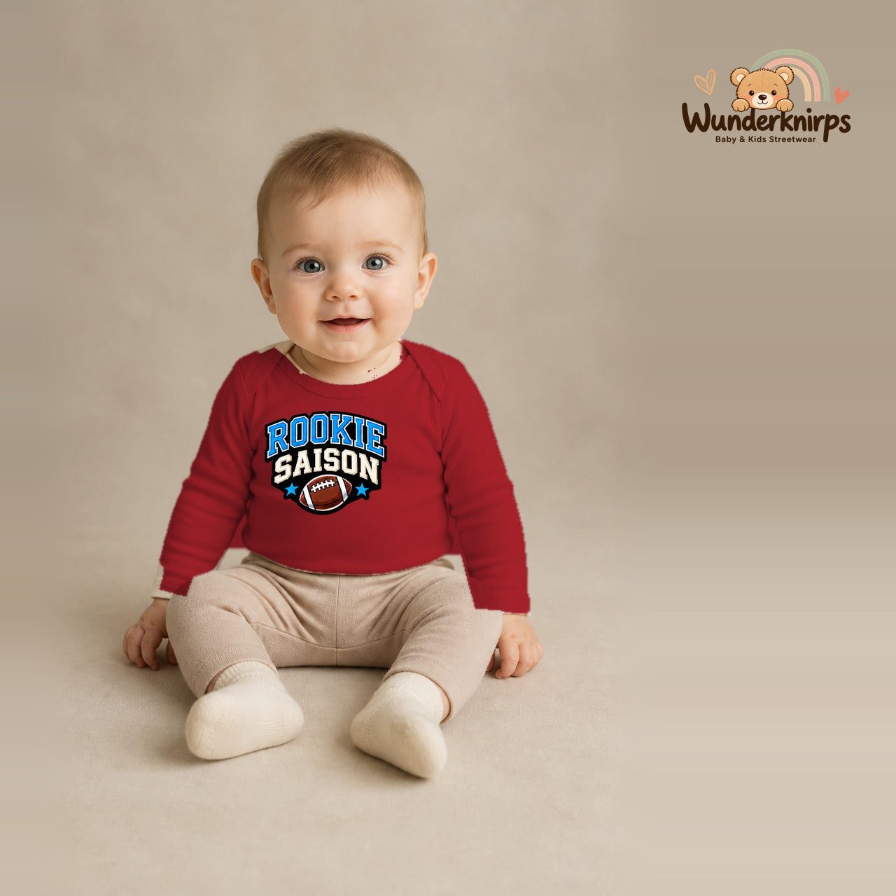 Babybody für Jungen in Rot mit Motiv „Rookie Saison“, getragen von einem Kind – Wunderknirps.