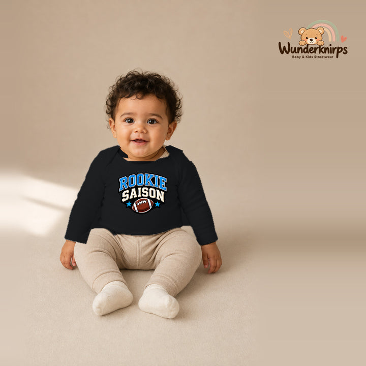 Babybody für Jungen in Schwarz mit Motiv „Rookie Saison“, getragen von einem Kind – Wunderknirps.