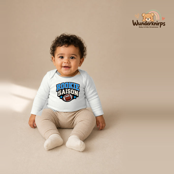 Babybody für Jungen in Weiß mit Motiv „Rookie Saison“, getragen von einem Kind – Wunderknirps.
