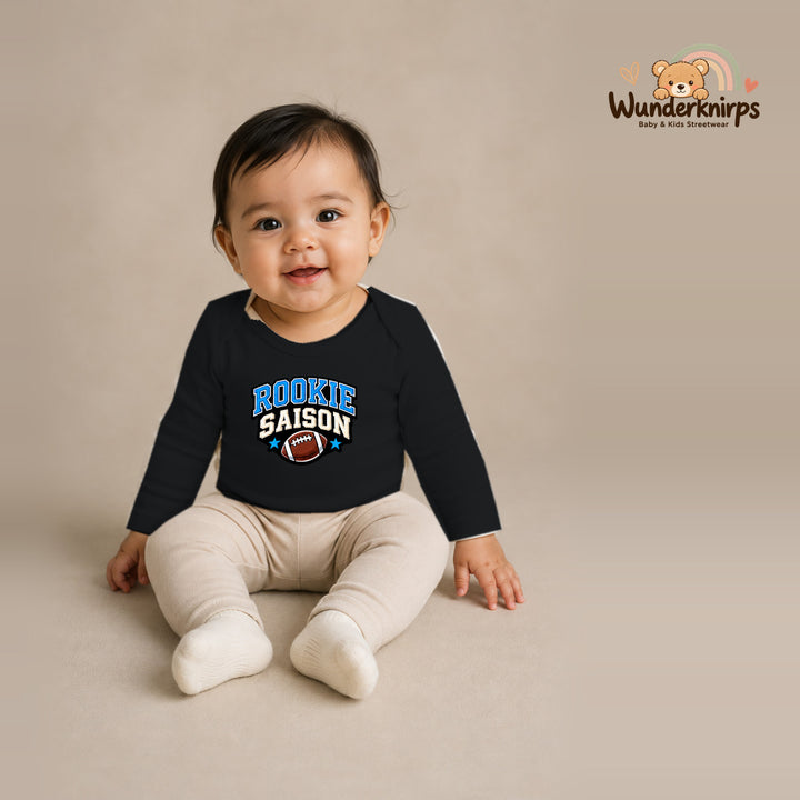 Babybody für Mädchen in Schwarz mit Motiv „Rookie Saison“, getragen von einem Kind – Wunderknirps.