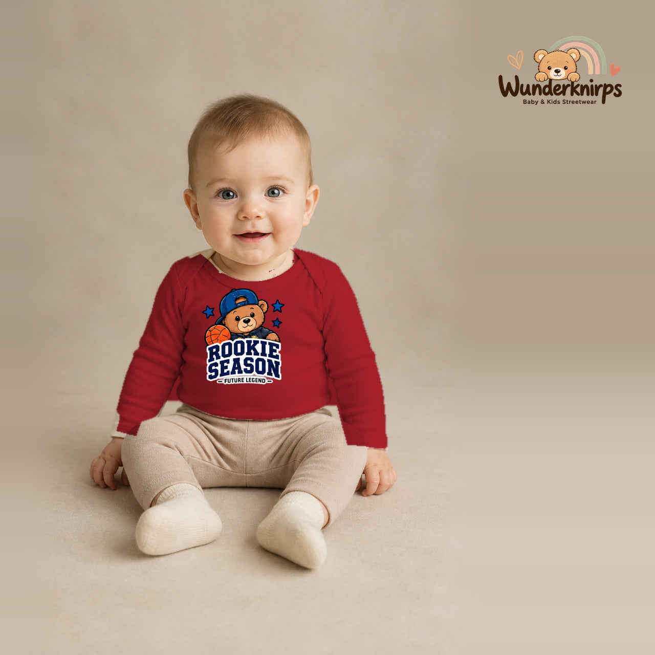 Babybody für Jungen in Rot mit Motiv „Rookie Season“, getragen von einem Kind – Wunderknirps.