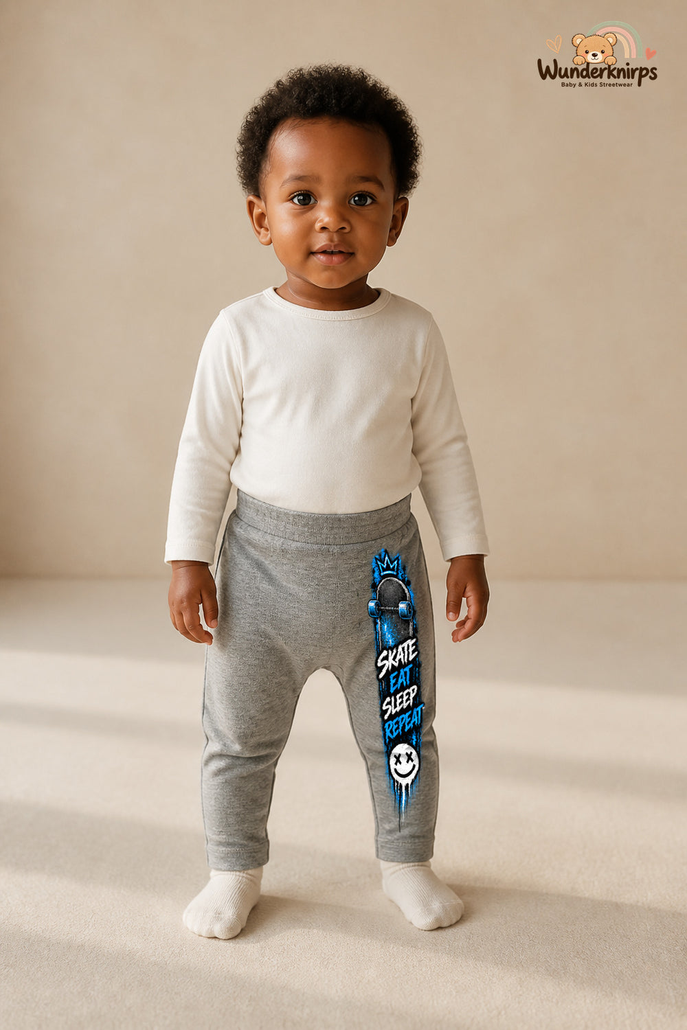 Skateboard Traumlook – Skate eat sleep repeat – Babyhose für Mädchen: Grau meliert mit Skateboard-Druck am Hosenbein – Wunderknirps.