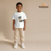 T-Shirt für Jungen in Weiß mit Motiv „Small Size Big Vibes“, getragen von einem Kind – Wunderknirps.