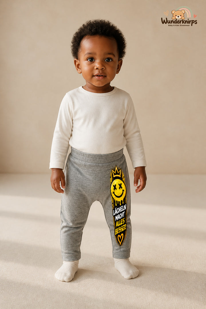 Kleine Weltentdeckerin: Lächeln macht alles besser – Babyhose für Mädchen: Grau meliert mit Smiley-Druck am Hosenbein – Wunderknirps.