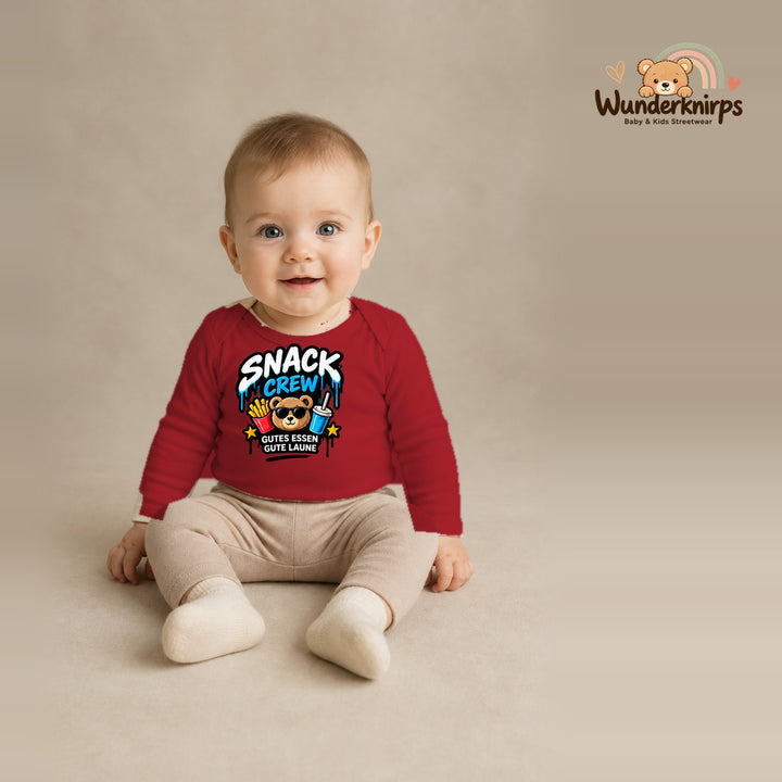 Babybody für Jungen in Rot mit Motiv „Snack Crew“, getragen von einem Kind – Wunderknirps.