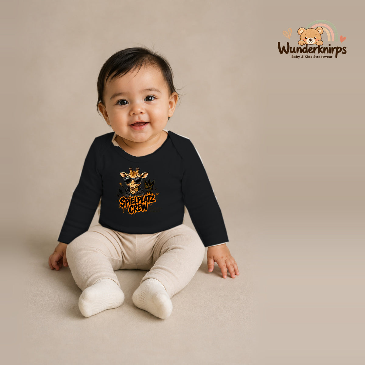 Babybody für Mädchen in Schwarz mit Motiv „Spielplatz Crew“, getragen von einem Kind – Wunderknirps.