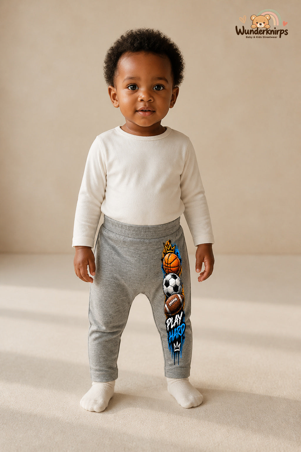 Sportbälle Lieblingslook – Play hard – Babyhose für Mädchen: Grau meliert mit Sportbälle-Druck am Hosenbein – Wunderknirps.