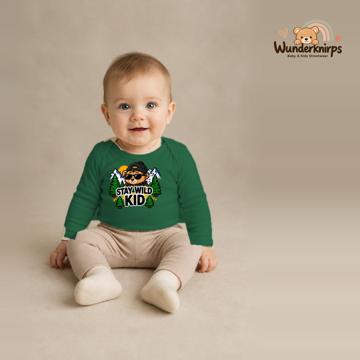 Babybody für Jungen in Grün mit Motiv „Stay Wild Kid“, getragen von einem Kind – Wunderknirps.