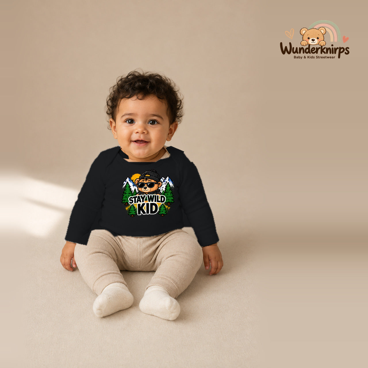Babybody für Jungen in Schwarz mit Motiv „Stay Wild Kid“, getragen von einem Kind – Wunderknirps.