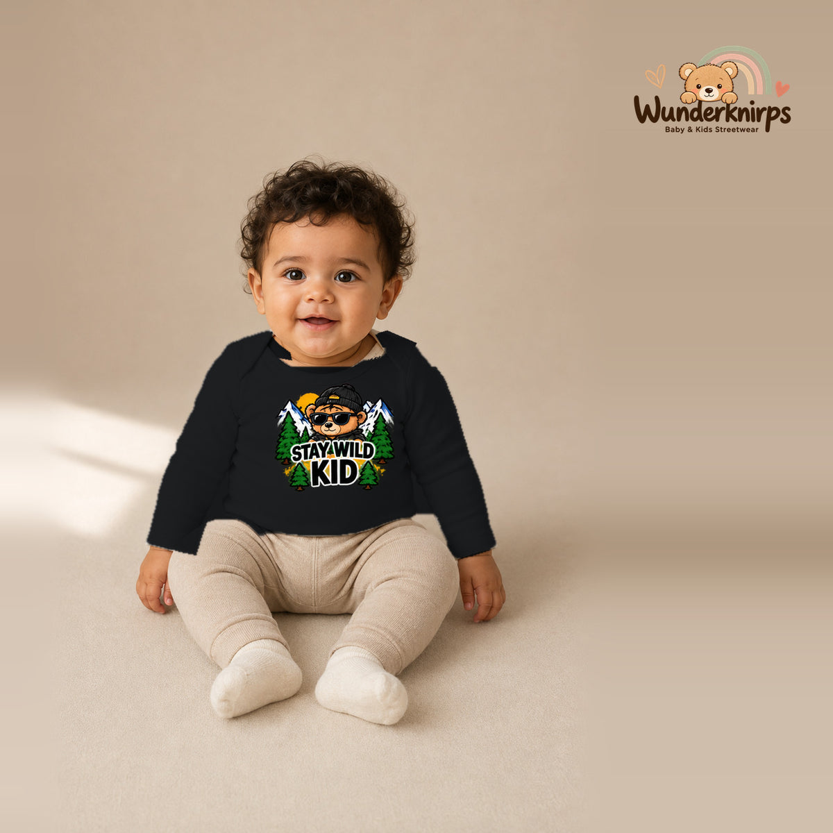 Babybody für Jungen in Schwarz mit Motiv „Stay Wild Kid“, getragen von einem Kind – Wunderknirps.
