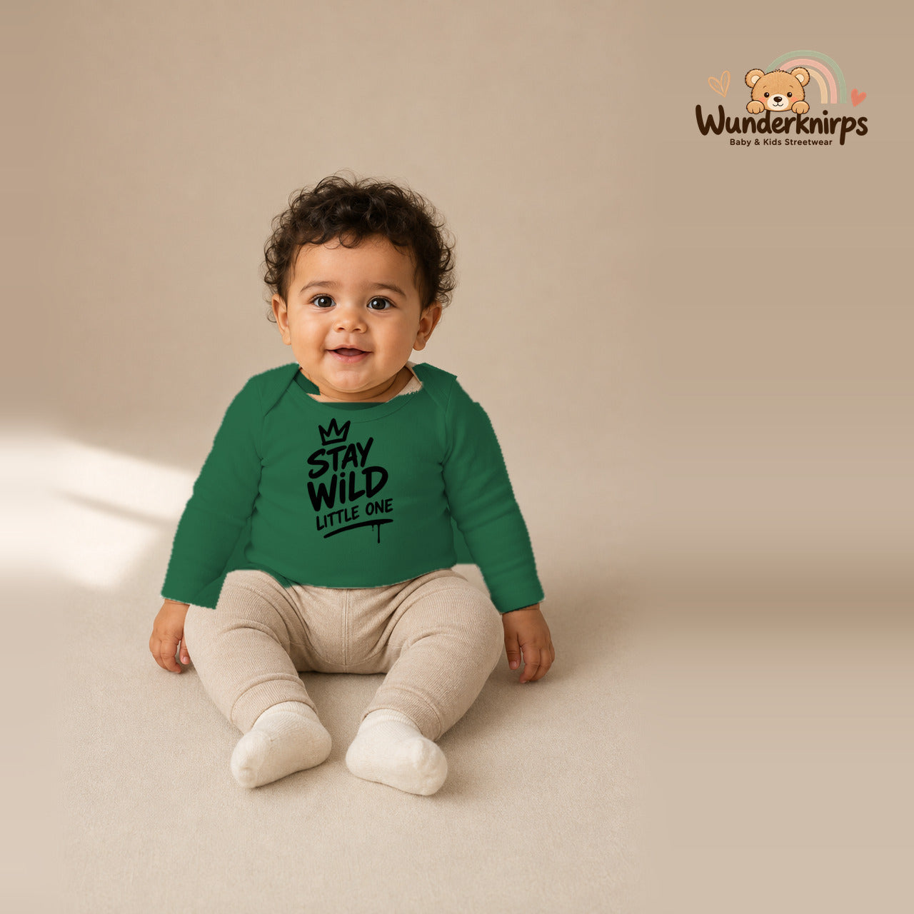 Babybody für Jungen in Grün mit Motiv „Stay Wild Little One“, getragen von einem Kind – Wunderknirps.