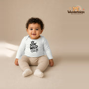 Babybody für Jungen in Weiß mit Motiv „Stay Wild Little One“, getragen von einem Kind – Wunderknirps.