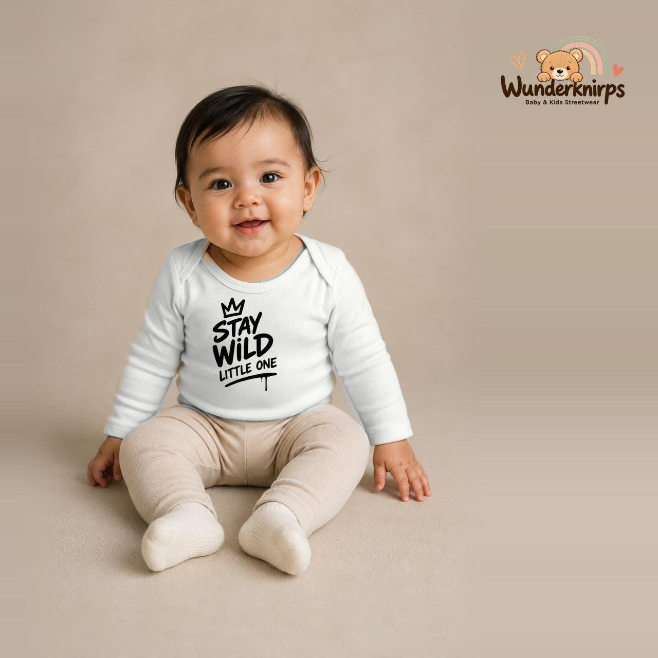 Babybody für Mädchen in Weiß mit Motiv „Stay Wild Little One“, getragen von einem Kind – Wunderknirps.