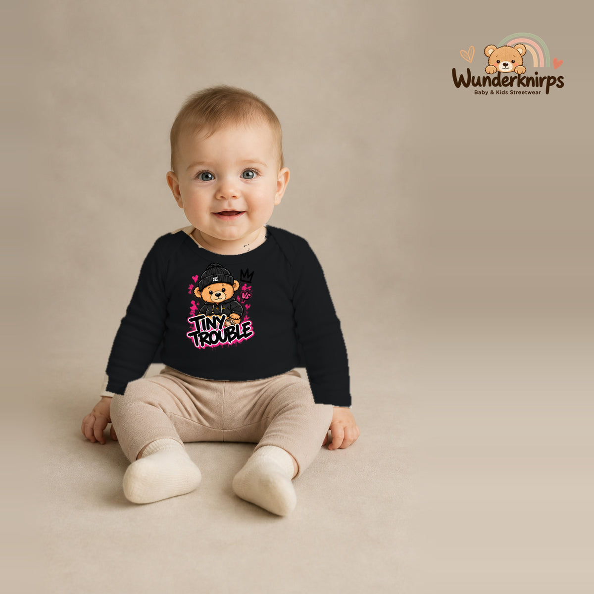 Babybody für Jungen in Schwarz mit Motiv „Tiny Trouble“, getragen von einem Kind – Wunderknirps.