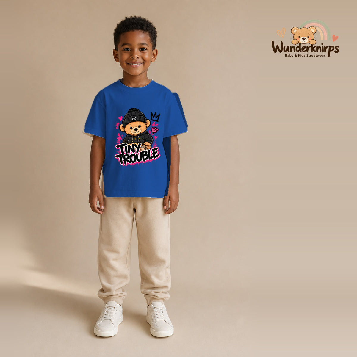T-Shirt für Jungen in Blau mit Motiv „Tiny Trouble“, getragen von einem Kind – Wunderknirps.