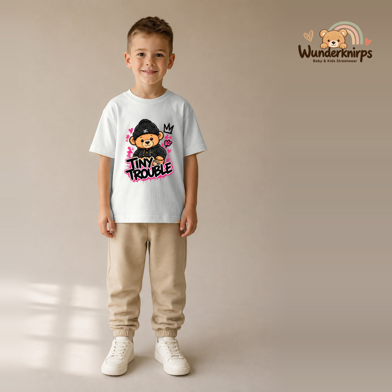 T-Shirt für Jungen in Weiß mit Motiv „Tiny Trouble“, getragen von einem Kind – Wunderknirps.